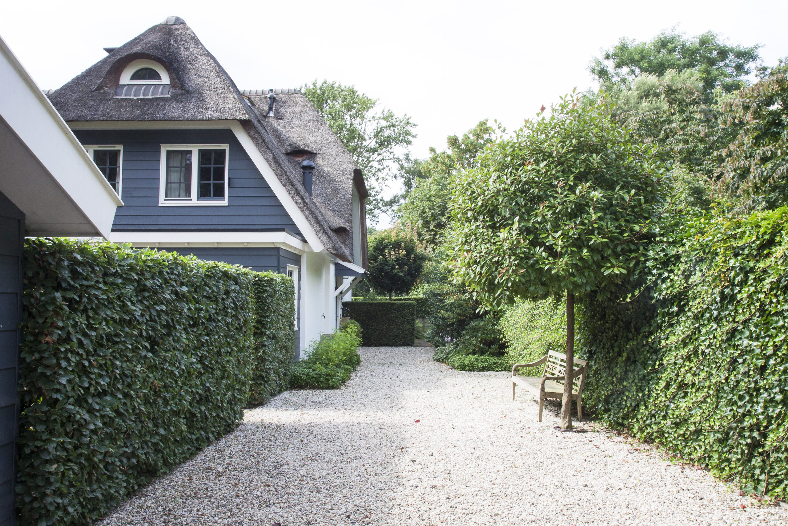 Bergweg tuin van uniek nieuwbouwhuis met rieten dak in het gooi