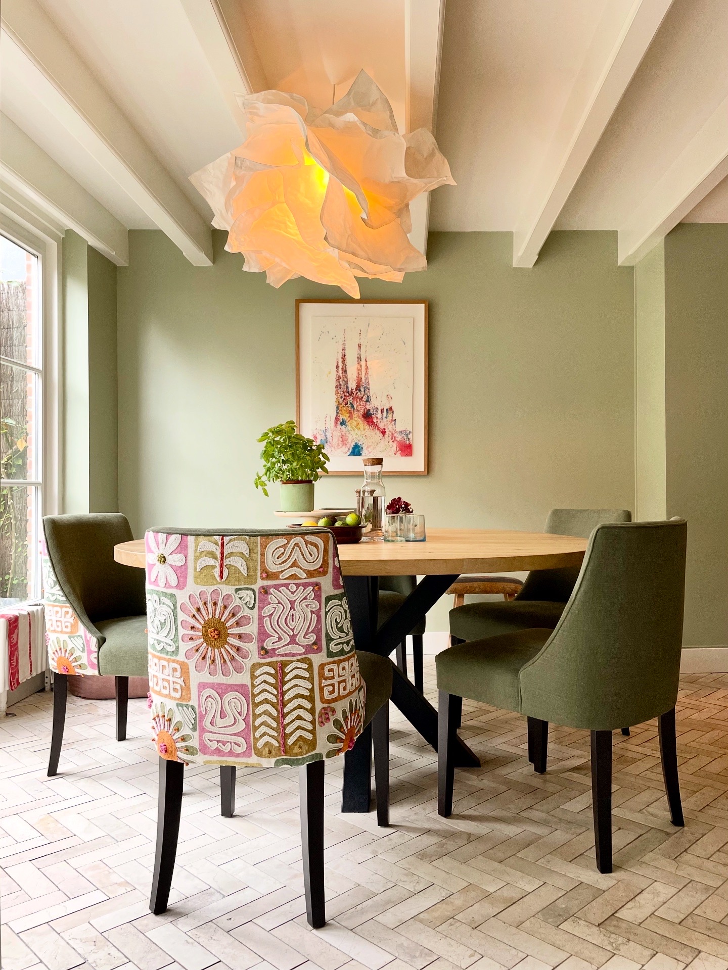 Lichte eetkamer met ronde houten tafel en kleurrijke stoelen in huis in Amstelveen
